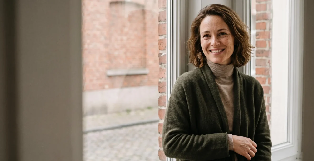 Portrait d'une femme souriante et sereine, incarnant l'acceptation de sa singularite physique loin des diktats de beaute