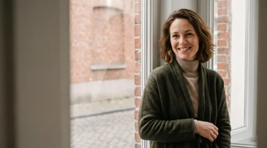 Portrait d'une femme souriante et sereine, incarnant l'acceptation de sa singularite physique loin des diktats de beaute